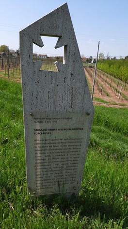Stele commemorativa a Haidar, circondata da un paesaggio verde e vigneti.