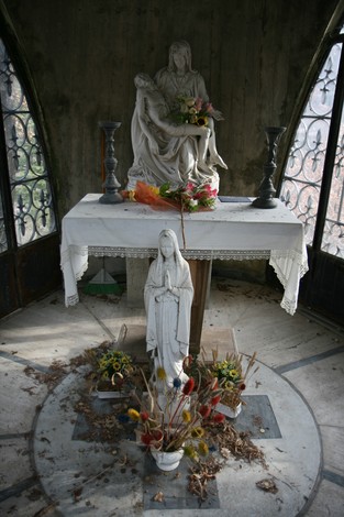 Cappella di Partina con statue sacre e decorazioni floreali in un ambiente suggestivo e raccolto.
