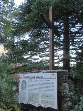 Croce a Tournoud, monumento dedicato alla memoria con pannello informativo, circondata da alberi.