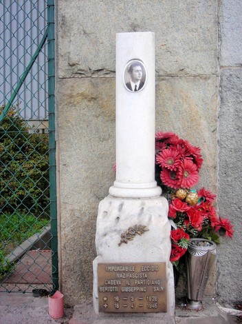 Cippo commemorativo dedicato a Giuseppe Bertotti, partigiano caduto, con fiori e una fotografia incastonata.