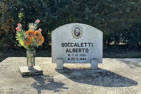 Cippo commemorativo dedicato ad Alberto Boccaletti, adornato da un vaso di fiori.