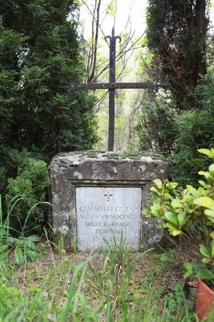 Cippo commemorativo nel verde, con una croce e una targa dedicata a Ciampelli Guido.