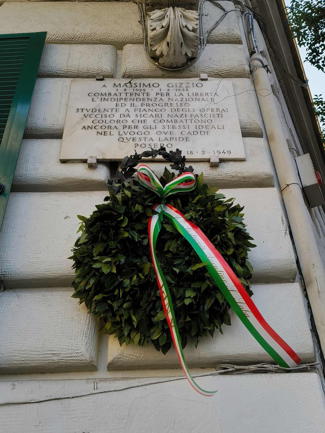 Lapide commemorativa a Massimo Gizzio, con una corona d'alloro e nastro tricolore in memoria dei caduti.