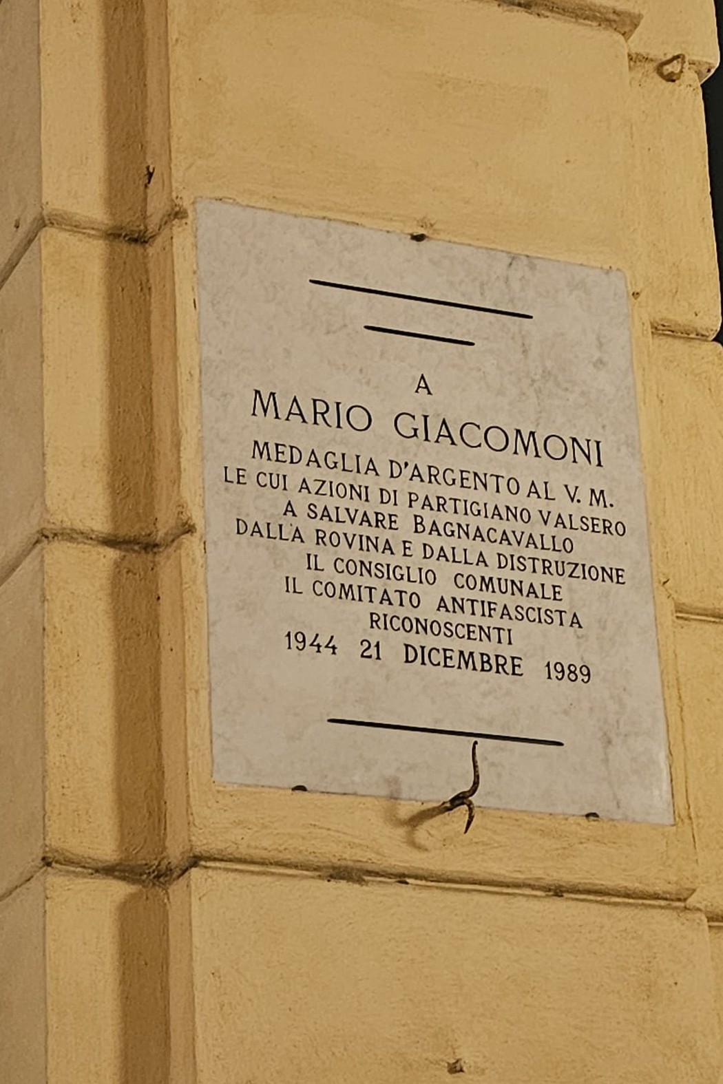 Lapide commemorativa a Mario Giacomoni, medaglia d’argento per atti di resistenza durante la Seconda Guerra Mondiale.