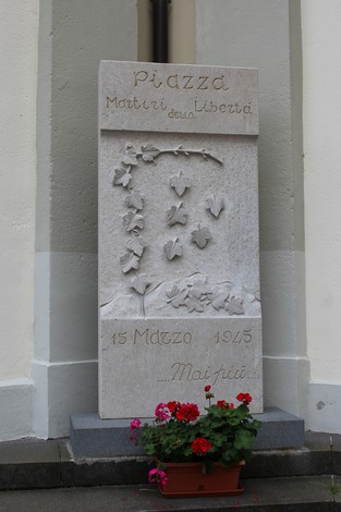 Monumento ai Martiri della Libertà, con decorazioni in pietra e fiori colorati in un vaso.