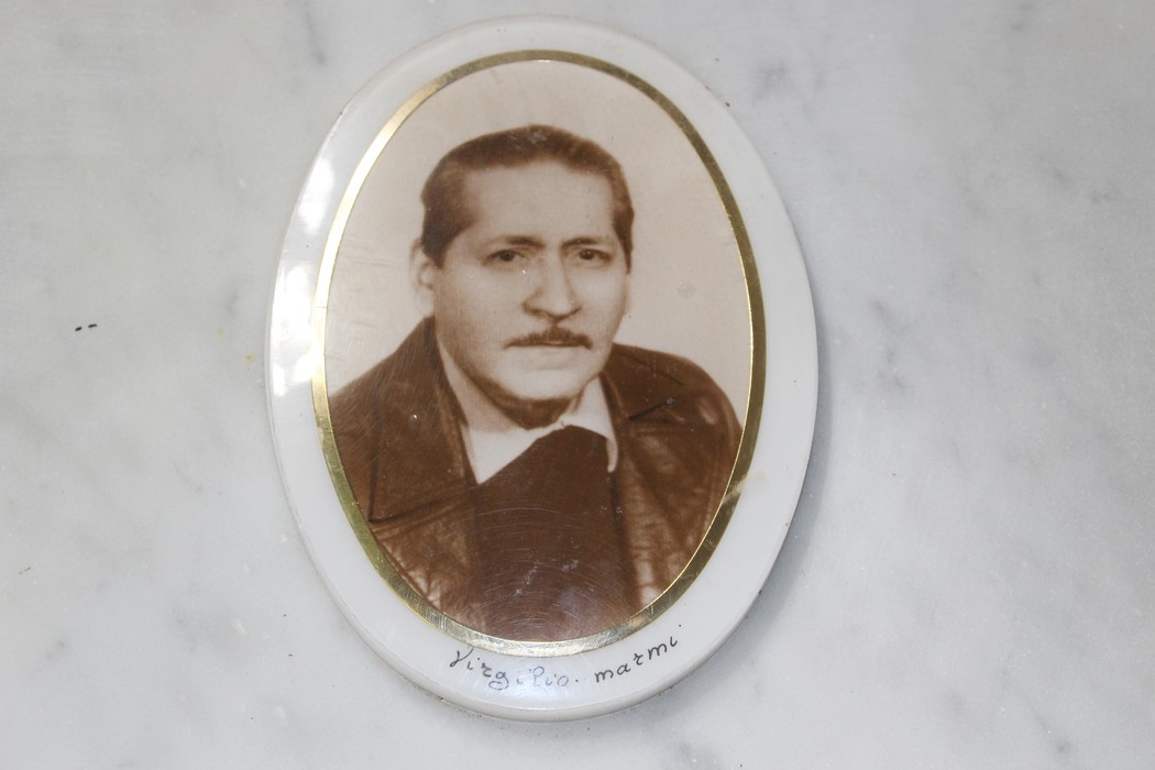 Immagine di una foto ovale di un uomo con giacca scura, incorniciata, probabilmente in memoria di un caduto.