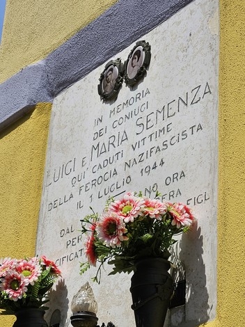 Lapide commemorativa dedicata ai coniugi Semenza, con fiori decorativi e una sobria cornice storica.