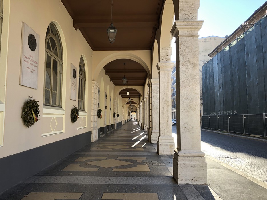 Portico con archi, pregno di storia, adornato da un'atmosfera di tranquillità e luce nel centro urbano.