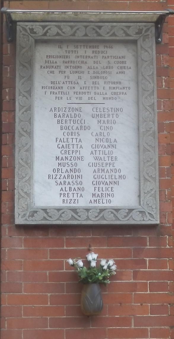 Lapide commemorativa ai caduti di Belvedere, con i nomi dei caduti incisi nel marmo e un vaso di fiori decorativo.
