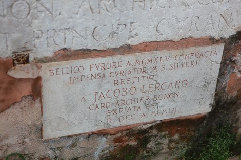 Lapide commemorativa per la ricostruzione di una croce, con iscrizioni storiche e decorazioni.