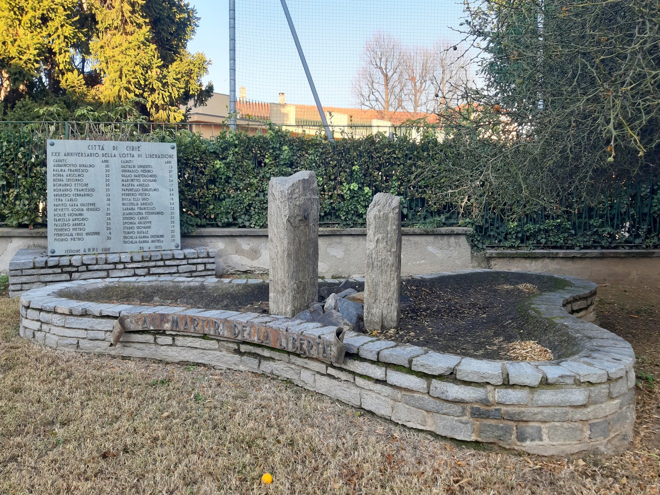 Monumento ai Martiri della Libertà, commemorazione in pietra con nomi incisi e area verde circostante.