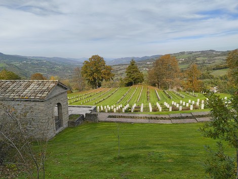 Cimitero di guerra sudafricano circondato da un paesaggio verde e colline, in un'atmosfera di rispetto e memoria.