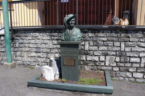 Monumento commemorativo con busto di Riccardi, situato in un'area verde e circondato da pietre.