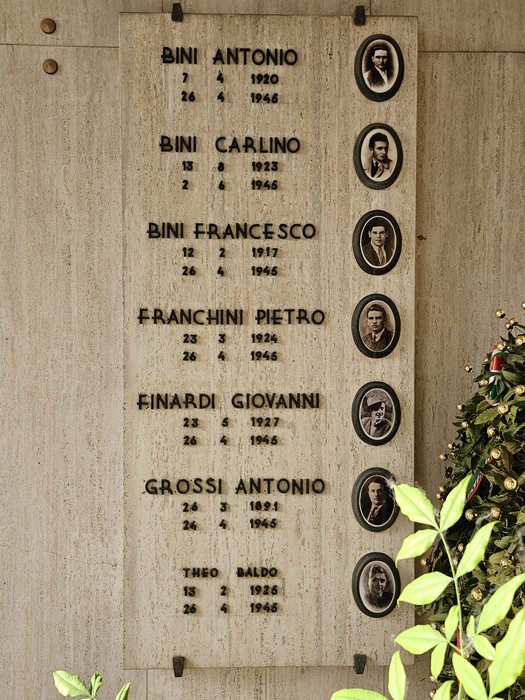 Monumento commemorativo dedicato ai caduti della Resistenza, con nomi e fotografie incastonati nella pietra.