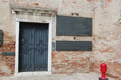 Monumento all'Olocausto con pareti in mattoni e testi commemorativi su placche di bronzo.