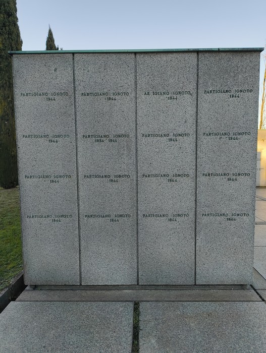 Monumento in pietra con iscrizioni commemorative, simbolo di memoria e onore. Ambiente tranquillo e ordinato.