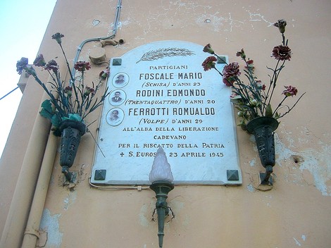 Lapide commemorativa dedicata ai partigiani Foscale, Rodini e Ferrotti, con fiori in omaggio.
