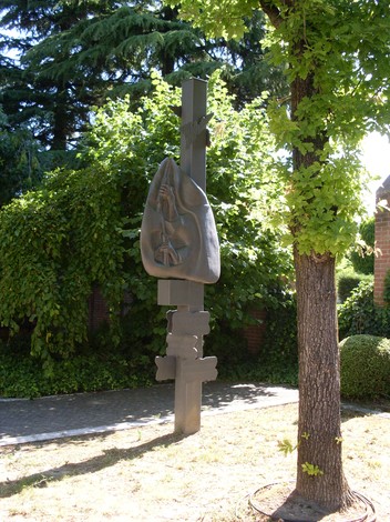 Monumento della Resistenza di Montecavolo, con scultura in metallo immersa nel verde di un giardino luminoso.