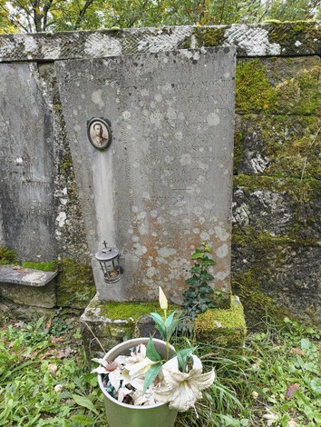 Sepolcri delle vittime di Giuncheto, con iscrizioni e fiori commemorativi, in un contesto naturale.