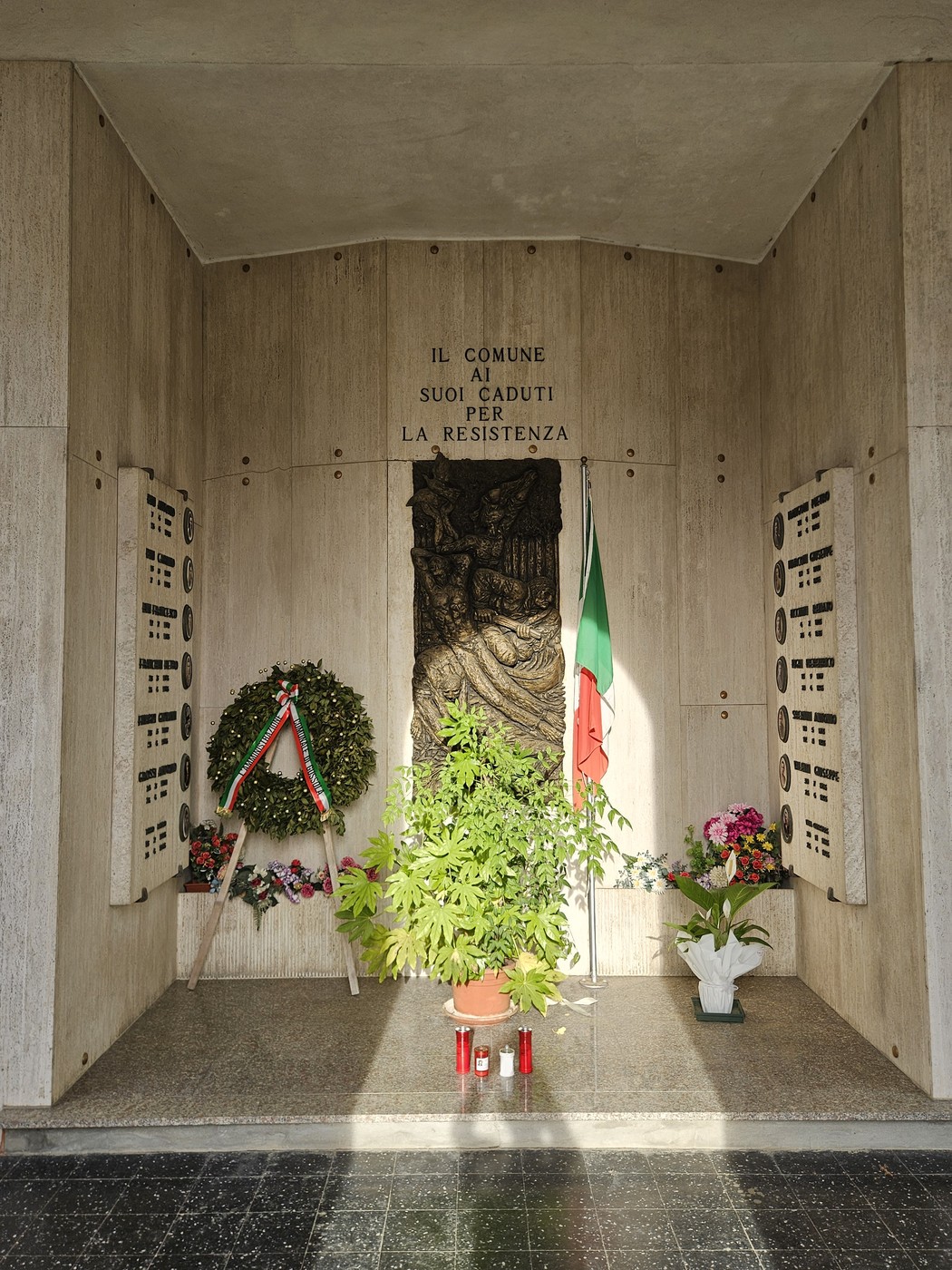 Sacrario dedicato ai Caduti per la Resistenza, con decorazioni floreali e bandiera italiana, ambiente sobrio e commemorativo.
