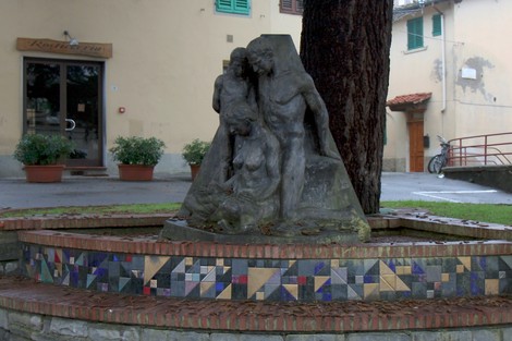 Monumento alle vittime civili, con figure scolpite che simboleggiano sofferenza e memoria, incastonato in un ambiente urbano.