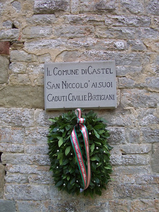 Lapide commemorativa dedicata ai civili e ai partigiani caduti, con corona d'alloro e nastri tricolore.