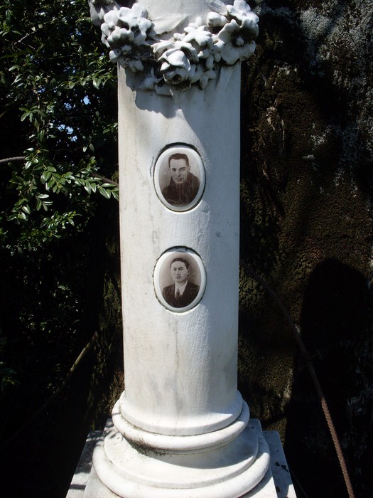 Cippo commemorativo con ritratti di Luppi e Bizzarri, immerso nella natura.