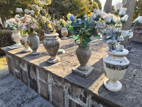 Vasi funerari con fiori artificiali su un'ara commemorativa in un sacrario ai caduti.