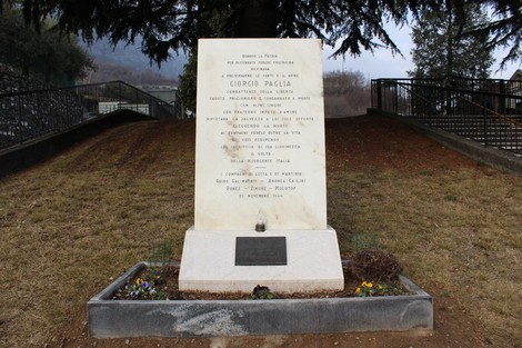 Lapide commemorativa dedicata a Giorgio Paglia e ai compagni caduti, circondata da un paesaggio naturale.
