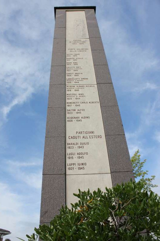 Monumento ai caduti di San Prospero, una stele di pietra con i nomi dei sacrifici e un cielo blu sopra.