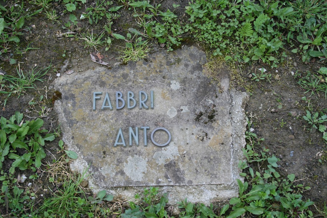 Monumento del cimitero di Stia, una semplice lapide immersa nel verde.
