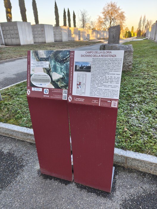 Campo della Gloria, sacrario della Resistenza, con pannelli informativi e monumenti circostanti in un ambiente sereno.