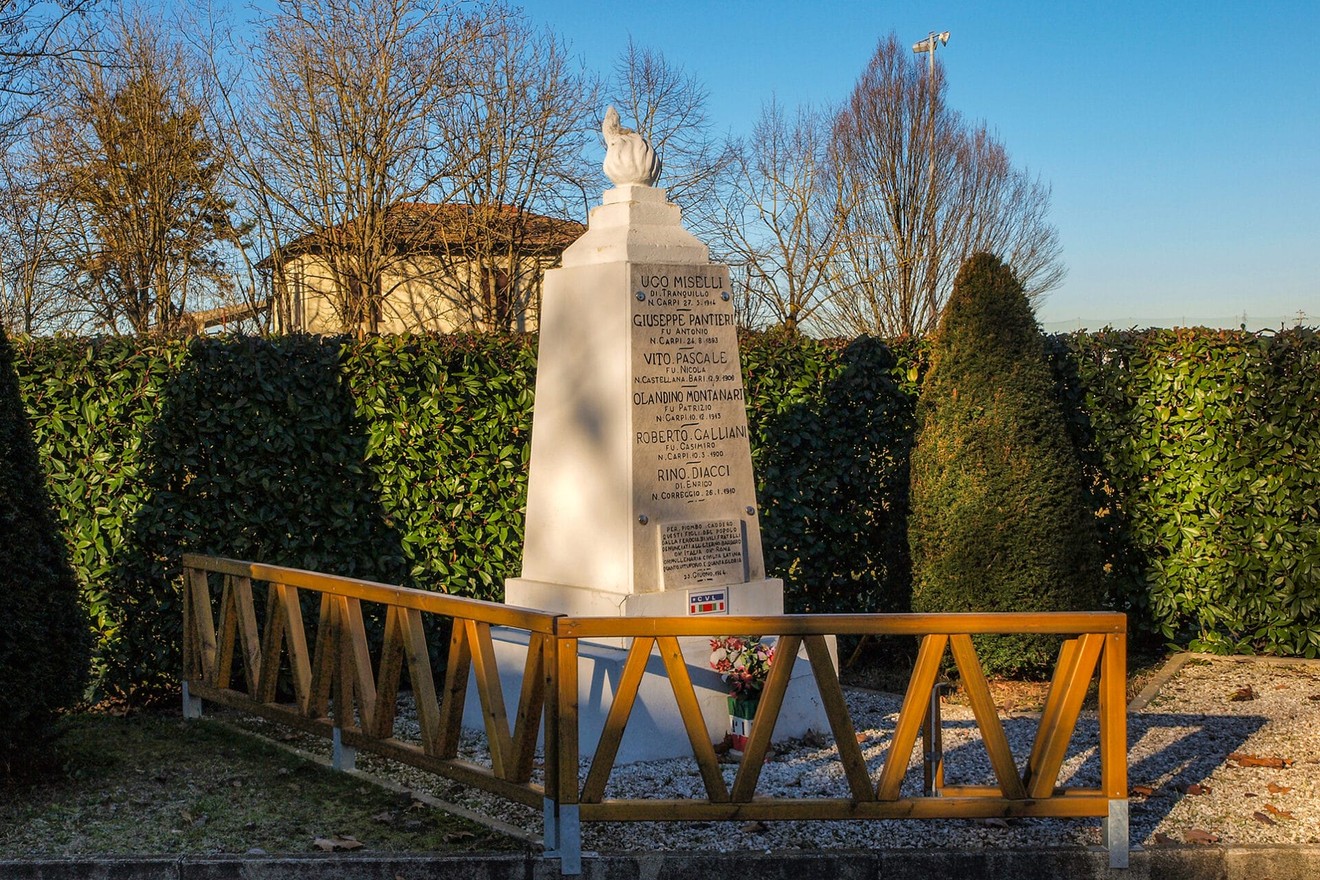 Monumento commemorativo dedicato a Miselli e ad altri caduti, circondato da alberi e siepi.