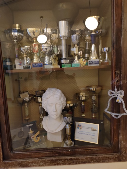 Lapide commemorativa dedicata a Mafalda di Savoia, esposta in una vetrina con trofei e riconoscimenti.