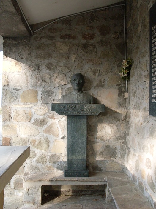 Busto commemorativo in pietra, situato all'interno del Sacrario di Ca' Marastoni, in un ambiente rustico.