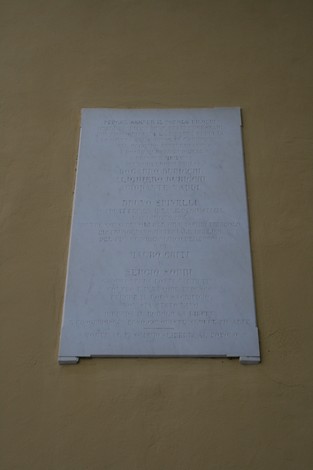 Lapide commemorativa affissa al municipio, dedicata alla memoria di eventi significativi.