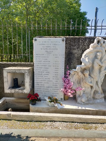 Monumento ai martiri di Villadose, con sculture e fiori in ricordo delle vittime. Ambiente luminoso e tranquillo.