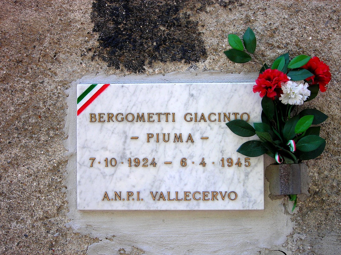 Lapide commemorativa di Giacinto Bergometti, con fiori, in memoria della sua vita e della sua storia.
