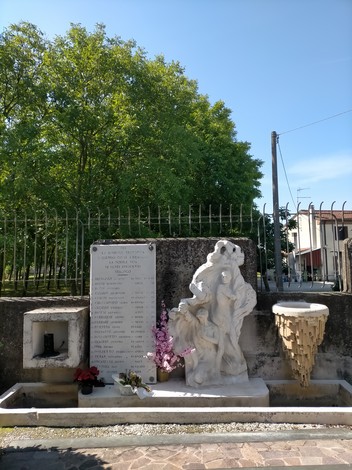 Monumento ai martiri di Villadose con statue e lapidi, immerso nel verde di un giardino pubblico.