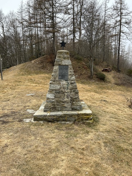 Monumento ai partigiani, struttura commemorativa in pietra circondata da alberi e un'area verde.