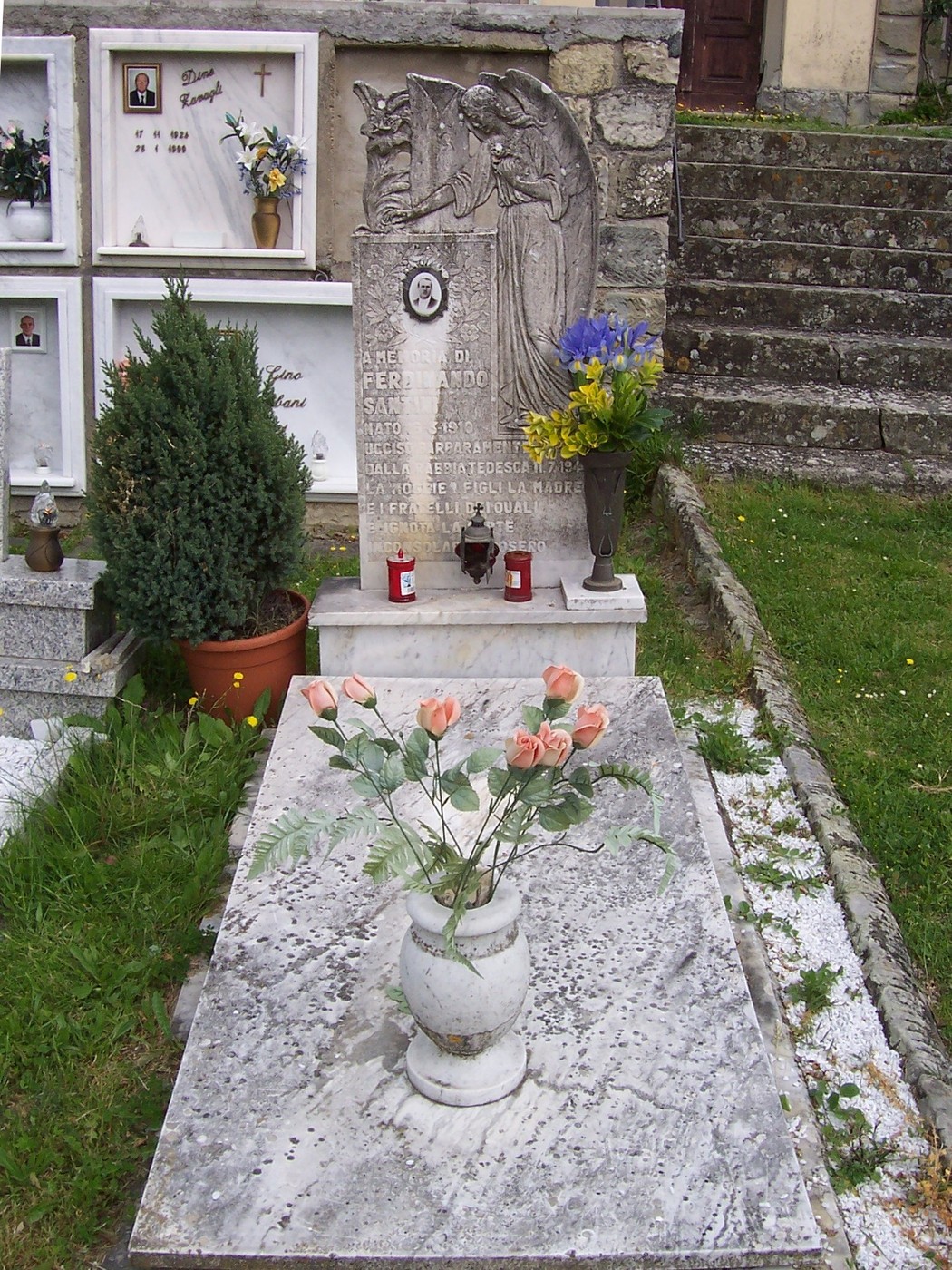 Sepolcro di Santini con angeli e decorazioni floreali, situato in un cimitero. Atmosfera di tranquilla memoria.