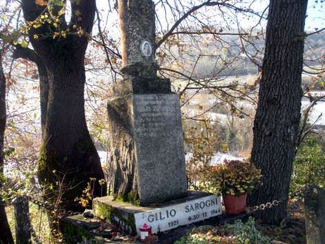 Cippo commemorativo dedicato a Cilgio Sarogni, immerso nella natura e circondato da alberi.