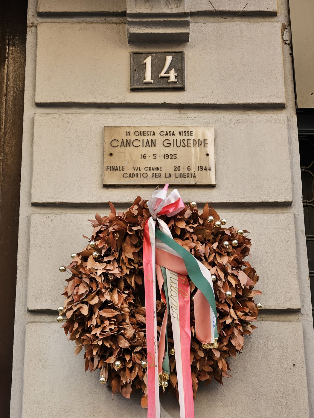 Lapide commemorativa di Cancian Giusepppe con una ghirlanda di foglie e nastri. Memoriale a un caduto per la libertà.