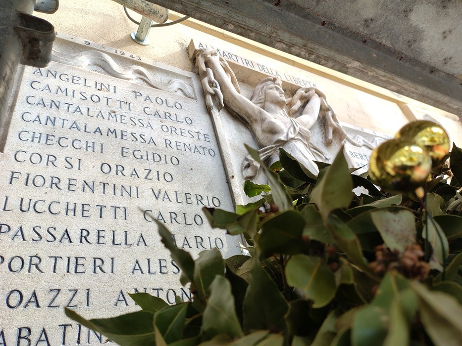 Lapide commemorativa in memoria dei caduti per la Libertà, adornata con un mazzo di foglie.
