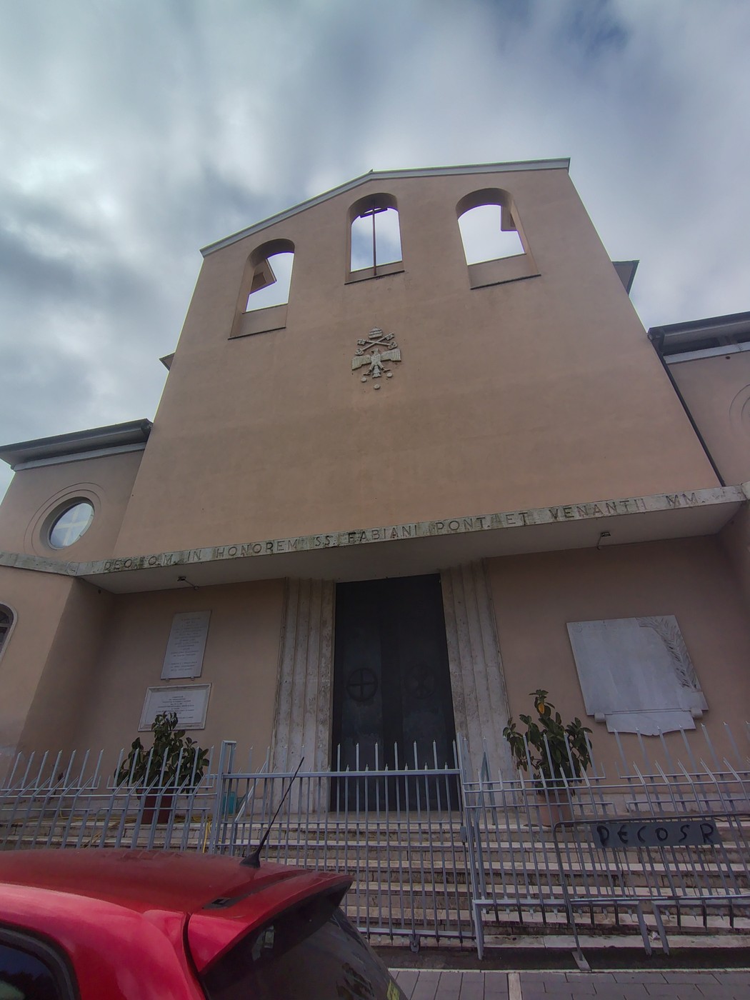 Lapidi commemorative ai caduti di guerra nel quartiere Tuscolano, con edifici storici sullo sfondo.