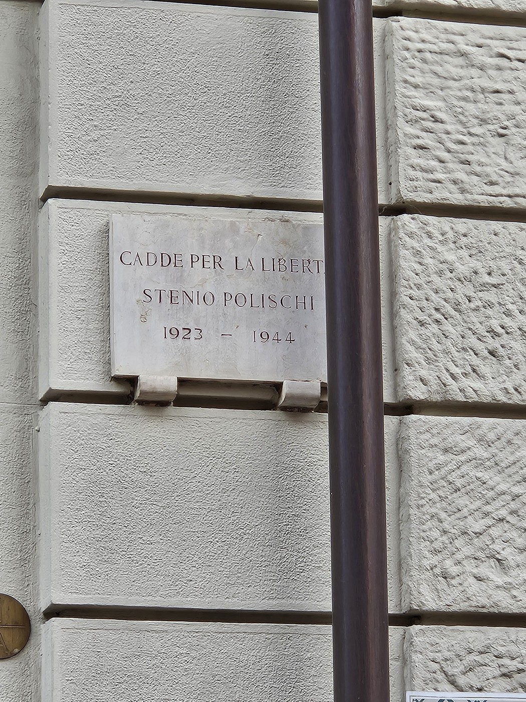 Lapide commemorativa dedicata a Stenio Polischi, situata su un muro in un contesto urbano.