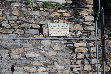 Lapide commemorativa di Giuseppe Zanchetta, affissa su una parete in pietra.