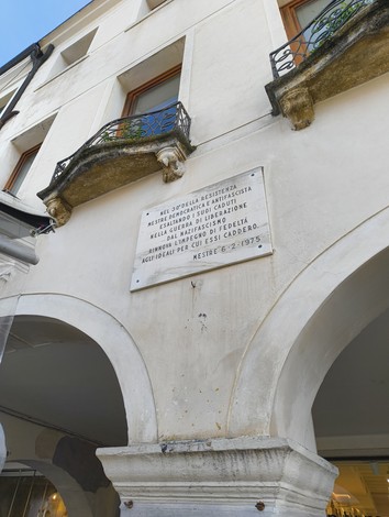 Lapide commemorativa sul muro di un edificio a Mestre, dedicata a un evento storico significativo.