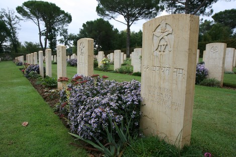 Cimitero militare di Arezzo, commemorazione dei caduti con lapidi e fiori in un'ambiente sereno.
