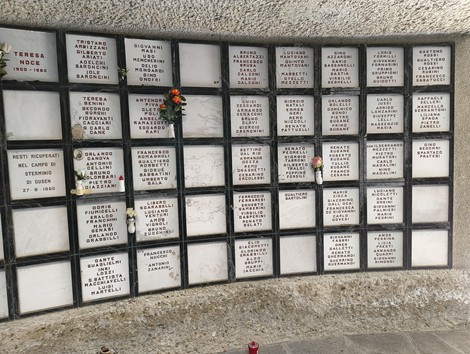 Monumento Ossario dei caduti partigiani, con targhe commemorative e fiori in ricordo dei defunti.
